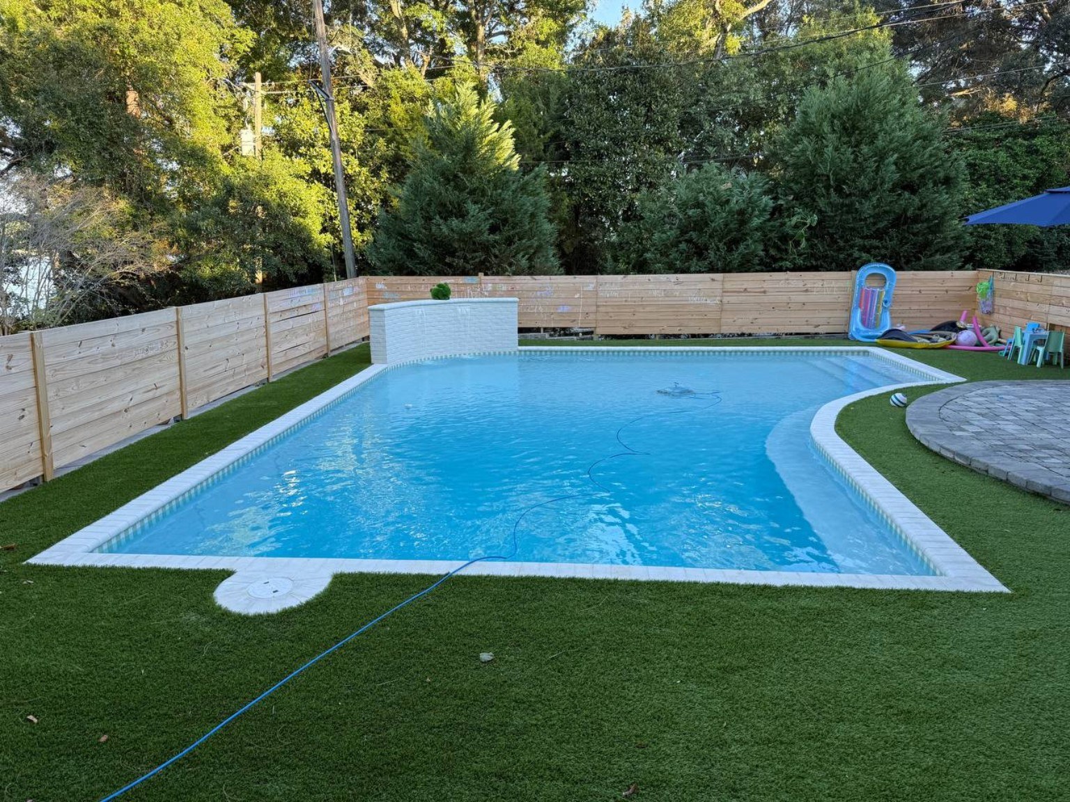 Freeform custom pool with raised wall and turf